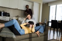 Amis assis sur le canapé dans le salon, jeux avec des lunettes VR — Photo de stock