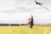 Happy senior couple flying kite in rural landscape — Stock Photo