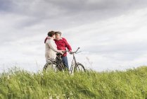 Couple aîné avec vélos embrasser dans le paysage rural — Photo de stock