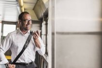 Lachender Geschäftsmann auf einer Fähre mit Handy und Kopfhörer — Stockfoto