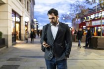 Великобритания, Лондон, бизнесмен на ходу проверяет свой телефон во время поездок по ночам — стоковое фото
