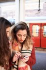 Royaume-Uni, Londres, deux femmes utilisant un téléphone portable au quai de la station de métro — Photo de stock