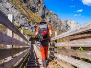 Spain, Asturia, Cantabrian Mountains, senior man on a hiking trip crossing a bridge — Stock Photo