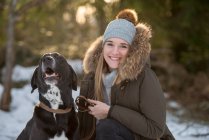 Portrait de jeune femme heureuse avec chien à la forêt d'hiver — Photo de stock