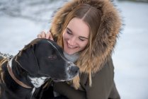 Joyeux jeune femme avec chien en hiver — Photo de stock