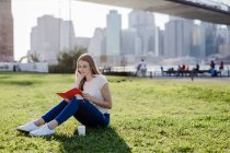 Giovane donna che esplora New York, si prende una pausa, legge un libro — Foto stock