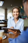 Smiling woman and man with tablet in a cafe — Stock Photo