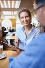 Smiling woman and man with tablet in a cafe — Stock Photo
