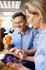 Smiling woman and man using tablet in a cafe — Stock Photo