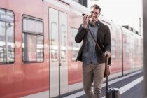 Glücklicher junger Mann mit Handy läuft auf Bahnsteig der S-Bahn — Stockfoto