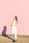 Felice giovane donna godendo il sole davanti a un muro rosa — Foto stock