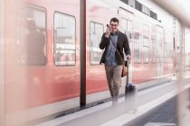 Glücklicher junger Mann mit Handy läuft auf Bahnsteig der S-Bahn — Stockfoto