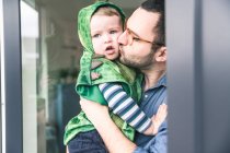 Pai beijando filho em um traje na porta do terraço em casa — Fotografia de Stock