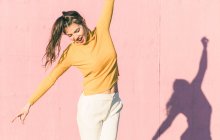 Giovane donna felice con le braccia outstreches davanti a un muro rosa — Foto stock