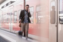 Lächelnder junger Mann mit Handy läuft auf S-Bahn-Bahnsteig — Stockfoto