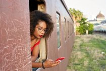 Young woman checking her phone at the window of a train — Stock Photo