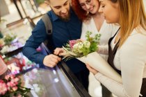 Florist wickelt Blumen für Paar im Blumenladen ein — Stockfoto