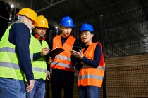 Workers standing in factory warehouse talking — Stock Photo