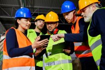 Workers in factory warehouse talking and using tablet — Stock Photo