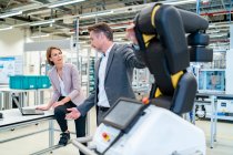 Businessman and businesswoman talking in a modern factory hall — Stock Photo