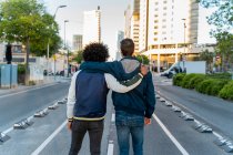 Rear view of two men embracing on the street in the city, Barcelona, Spain — Stock Photo