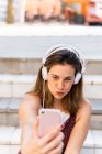 Young woman using smartphone and listening music, taking a selfie — Stock Photo