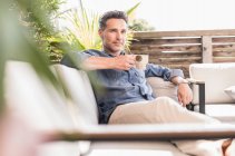 Hombre seguro relajándose en la terraza, tomando café - foto de stock