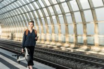 Young woman with electric scooter at the train station — Stock Photo