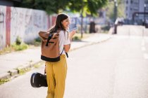 Молодая женщина с футляром для скрипки с мобильного телефона на улице — стоковое фото