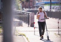 Junger Mann mit Elektroroller mit Handy auf der Straße — Stockfoto