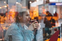 Jeune femme dans un café boire et profiter d'un café — Photo de stock
