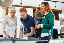 Family shopping for a new kitchen in showroom looking at papers — Stock Photo