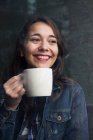 Jeune femme dans un café avec une tasse de café et regardant de côté — Photo de stock