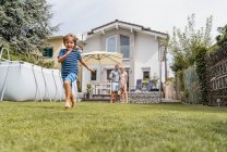 Ragazzo che corre in giardino con i genitori a guardare — Foto stock