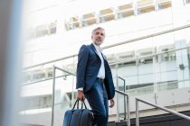 Mature businessman holding bag walking down stairs in the city — Stock Photo