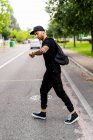 Молодий чоловік переходить вулицю в місті і перевіряє час на годиннику на зап'ясті — стокове фото