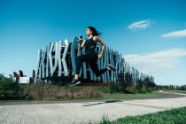 Jovem jogger feminino em um caminho em frente a um edifício moderno — Fotografia de Stock