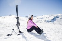 Woman taking a break after skiing sitting on the snowy ground in Sierra Nevada, Andalusia, Spain — Stock Photo