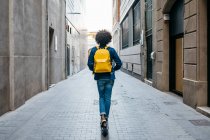 Back view of young man with yellow backpack on E-Scooter in the city, Barcelona, Spain — Stock Photo