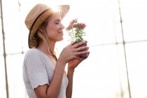 Bella giovane donna che annusa a fiore nella serra — Foto stock
