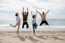Amici esuberanti che saltano sulla spiaggia — Foto stock