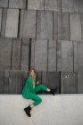 Blond young woman wearing green pantsuit sitting on a wall, Vienna, Austria — Stock Photo