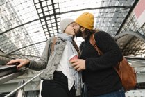 Coppia giovane che si bacia su una scala mobile alla stazione, Berlino, Germania — Foto stock