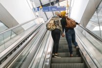 Jeune couple embrassant dans un escalier roulant à la gare, Berlin, Allemagne — Photo de stock