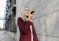 Blond businesswoman using smartphone in the city — Stock Photo