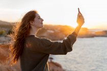Потихла молода жінка, яка зробила селфі біля узбережжя на заході сонця в Івіці (Іспанія). — стокове фото