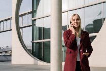 Blond businesswoman using smartphone in the background modern building — Stock Photo