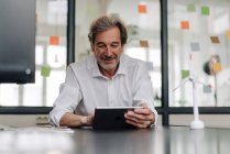 Uomo d'affari anziano che utilizza tablet in sala conferenze in ufficio — Foto stock