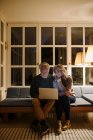 Coppia anziana che utilizza il computer portatile sul divano a casa di notte — Foto stock