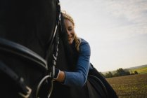 Zärtliche Frau zu Pferd auf einem Feld auf dem Land — Stockfoto